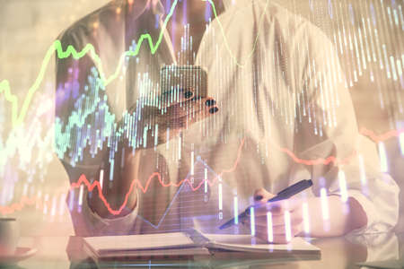 Double exposure of financial graph sketch hologram and woman holding and using a mobile device....
