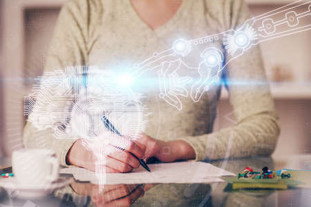 Double exposure of writing hand on background with brain hologram. Concept of learning.