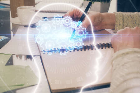 Double exposure of writing hand on background with brain hologram. Concept of learning.