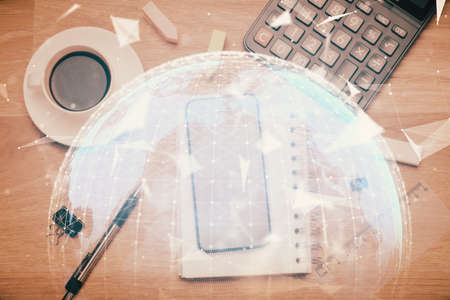 Double exposure of business theme hologram over desktop with phone. Top view. Mobile international trade connection concept.の写真素材