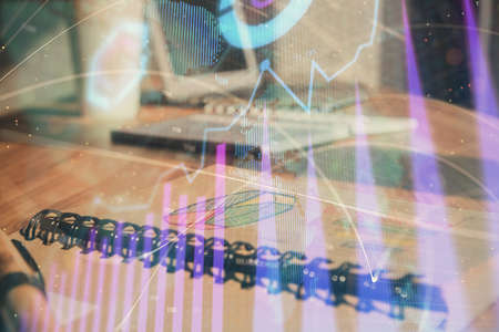 Double exposure of financial graph drawings and desk with open notebook background. Concept of forex...