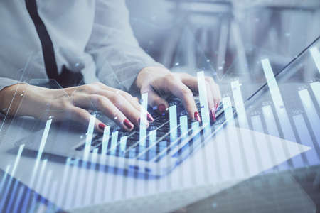 Multi exposure of woman hands typing on computer and financial graph hologram drawing. Stock market...