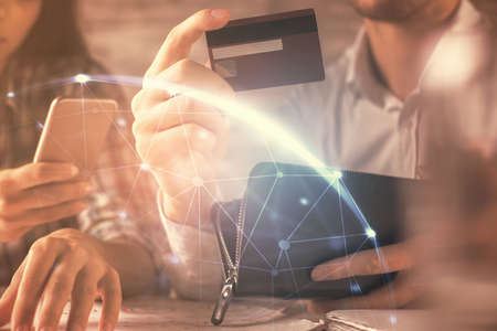 Double exposure of man and woman on-line shopping holding a credit card and social network theme hologram drawing. People connecting and E-commerce pay on-line concept.の写真素材
