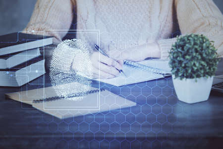 Blue fingerprint hologram over hands taking notes background. Concept of security. Double exposureの写真素材