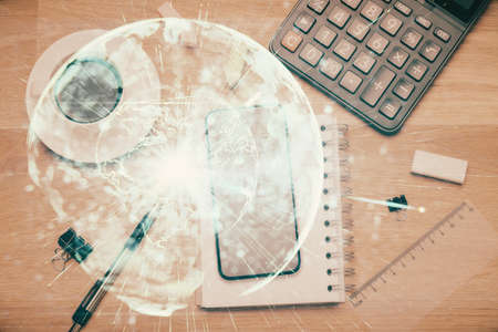 Double exposure of business theme hologram over desktop with phone. Top view. Mobile international trade connection concept.の写真素材