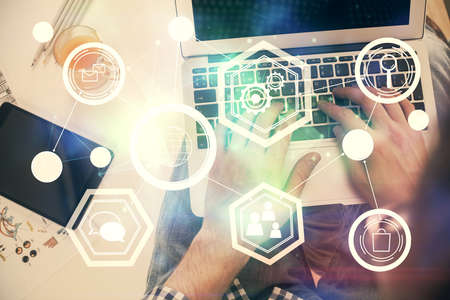 Double exposure of mans hands typing over computer keyboard and social network theme hologram drawing. Top view. People connection web concept.の写真素材