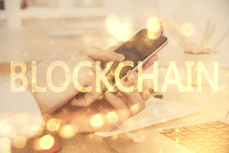 Double exposure of mans hands holding and using a phone and crypto currency blockchain theme drawing.の写真素材