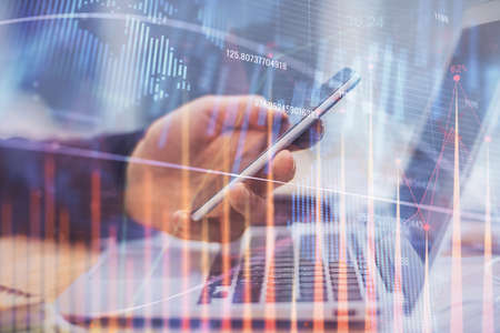 Double exposure of mans hands holding and using a phone and financial graph drawing. Analysis...