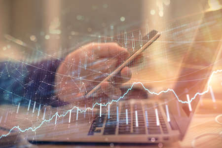 Double exposure of mans hands holding and using a phone and financial graph drawing. Analysis concept.の写真素材