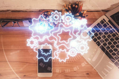 Double exposure of business theme hologram over desktop with phone. Top view. Mobile international...