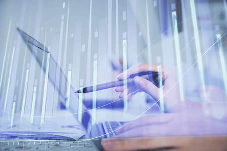 Multi exposure of woman hands typing on computer and financial graph hologram drawing. Stock market...