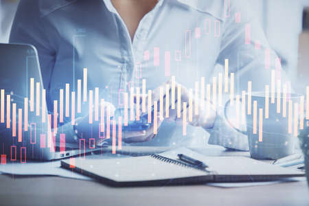 Double exposure of forex chart sketch hologram and woman holding and using a mobile device....