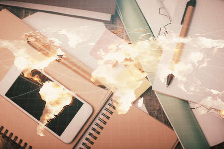Double exposure of business theme hologram over desktop with phone. Top view. Mobile international trade connection concept.の写真素材