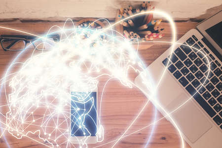Double exposure of business theme hologram over desktop with phone. Top view. Mobile international...