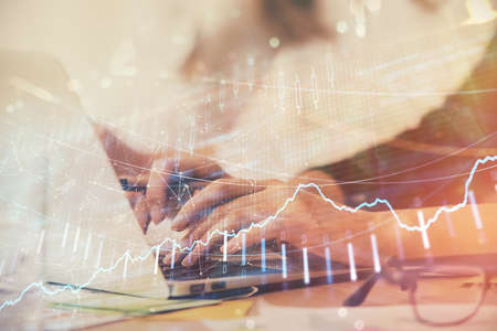 Multi exposure of woman hands typing on computer and financial graph hologram drawing. Stock market...