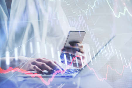Double exposure of financial graph sketch hologram and woman holding and using a mobile device....