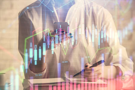Double exposure of financial graph sketch hologram and woman holding and using a mobile device....