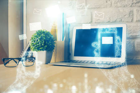 Desktop computer background in office and flying envelops hologram drawing. Multi exposure. Electronic mail concept.の写真素材