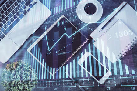 Double exposure of forex chart hologram over desktop with phone. Top view. Mobile trade platform...