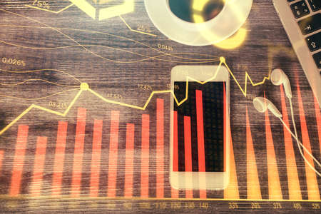 Double exposure of forex chart hologram over desktop with phone. Top view. Mobile trade platform concept.の写真素材