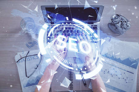 Double exposure of woman hands working on computer and SEO hologram drawing. Top View. Search...