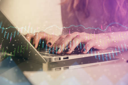 Double exposure of woman hands typing on computer and forex chart hologram drawing. Stock market invest concept.の写真素材