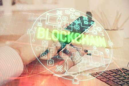 Double exposure of mans hands holding and using a phone and crypto currency blockchain theme...