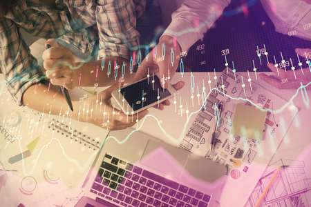Double exposure of forex graph drawing and man and woman working together holding and using a mobile...