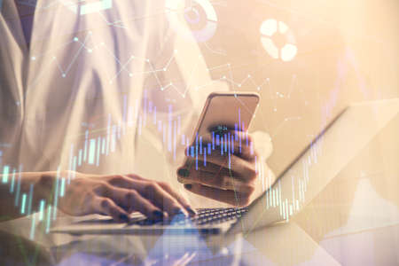 Double exposure of financial graph sketch hologram and woman holding and using a mobile device....