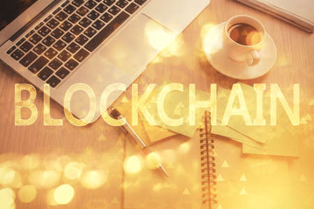 Blockchain theme hologram drawings over computer on the desktop background. Top view. Double...