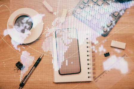Double exposure of business theme hologram over desktop with phone. Top view. Mobile international trade connection concept.の写真素材