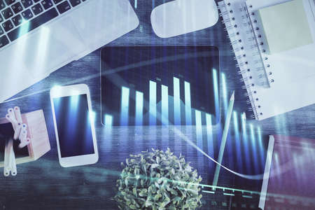 Double exposure of forex chart hologram over desktop with phone. Top view. Mobile trade platform...
