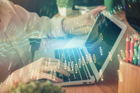 Double exposure of woman hands typing on computer and forex chart hologram drawing. Stock market...
