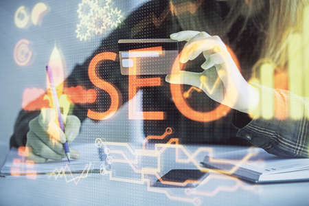 Double exposure of woman on-line shopping holding a credit card and SEO hologram drawing. Search optimization E-commerce concept.の写真素材