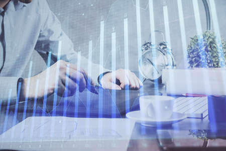 Double exposure of mans hands holding and using a phone and financial graph drawing. Analysis...