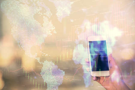 Double exposure of forex chart sketch hologram and woman holding and using a mobile device. Stock market concept.の写真素材
