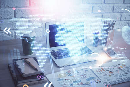 Double exposure of desktop with computer and world map hologram. International data network concept.