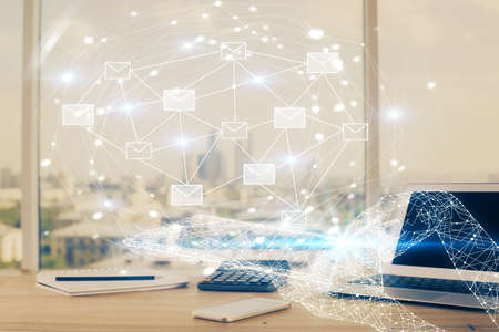 Desktop computer background in office and flying envelops hologram drawing. Double exposure. Electronic mail concept.の写真素材