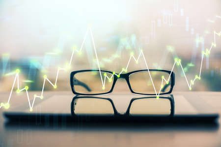 Financial graph hologram with glasses on the table background. Concept of business. Double exposure.