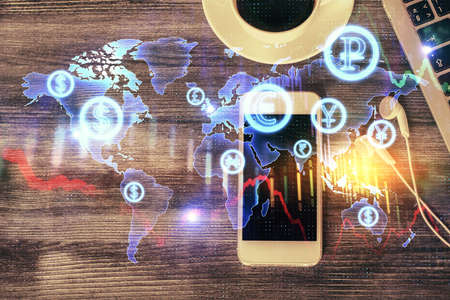 Double exposure of forex chart hologram over desktop with phone. Top view. Mobile trade platform...