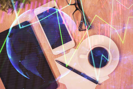 Double exposure of forex chart hologram over desktop with phone. Top view. Mobile trade platform...