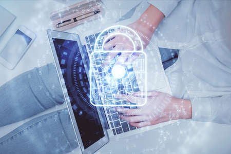 Double exposure of woman hands working on computer and lock hologram drawing. Top View. Security...