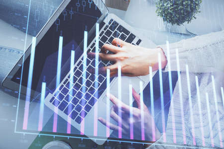 Double exposure of woman hands working on computer and forex chart hologram drawing. Top View....