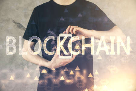Double exposure of mans hands holding and using a phone and crypto currency blockchain theme...