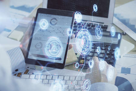 Double exposure of mans hand holding and using a digital device and data theme hologram drawing....