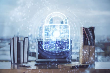 Double exposure of desktop with computer and lock icon hologram. Concept of data safety.