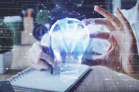 Drawing bulb over womans hands taking notes background. Concept of idea. Double exposureの写真素材