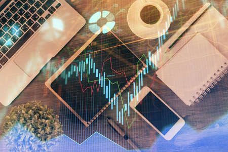 Double exposure of forex chart hologram over desktop with phone. Top view. Mobile trade platform concept.の写真素材