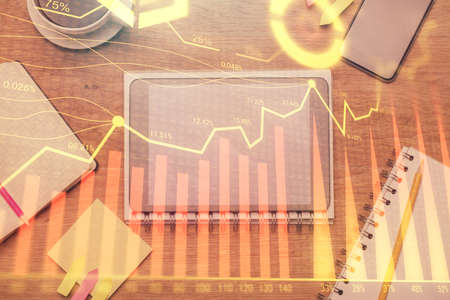Double exposure of forex chart hologram over desktop with phone. Top view. Mobile trade platform...