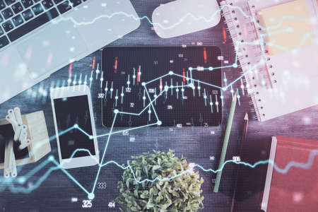Double exposure of forex chart hologram over desktop with phone. Top view. Mobile trade platform concept.の写真素材